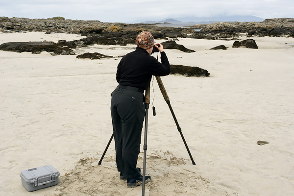 Jacky taking a landscape photograph on a beach in Scotland